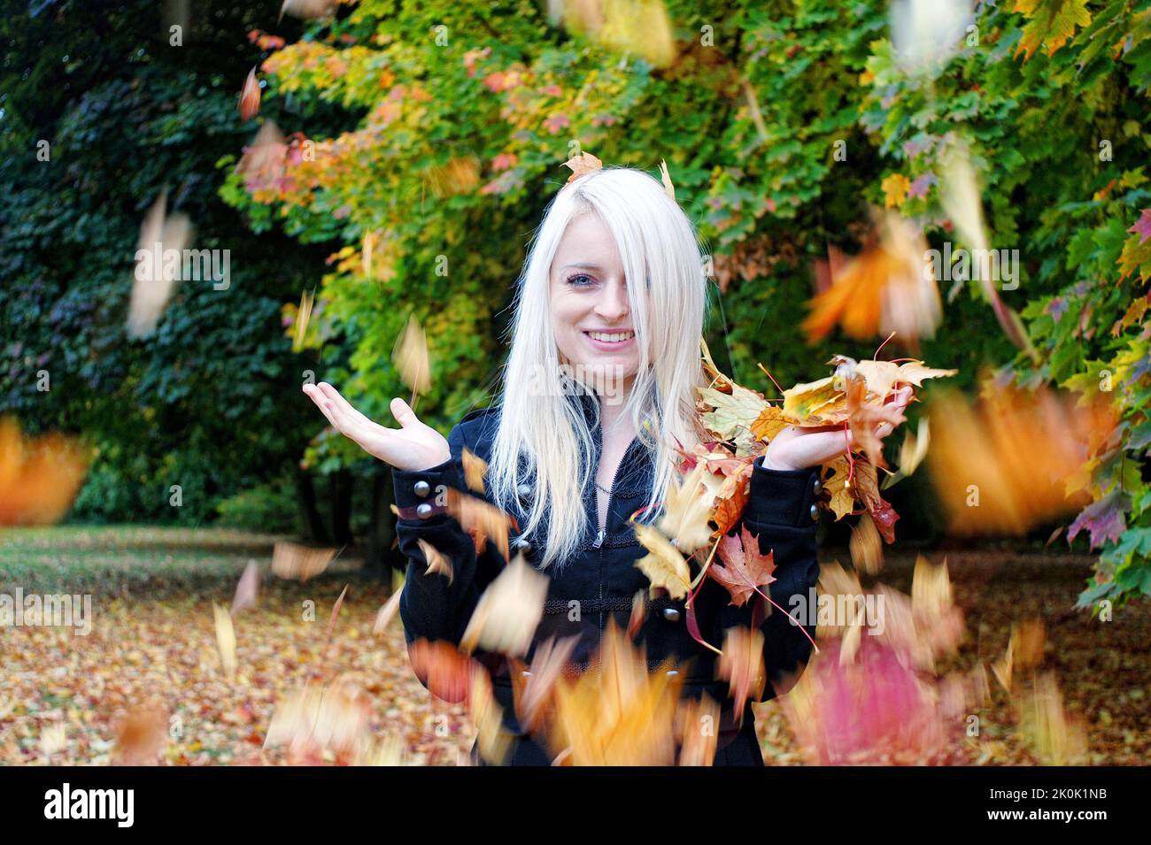 Der herbstliche Herbst macht Spaß in einem Park mit einer blonden Frau Stockfoto