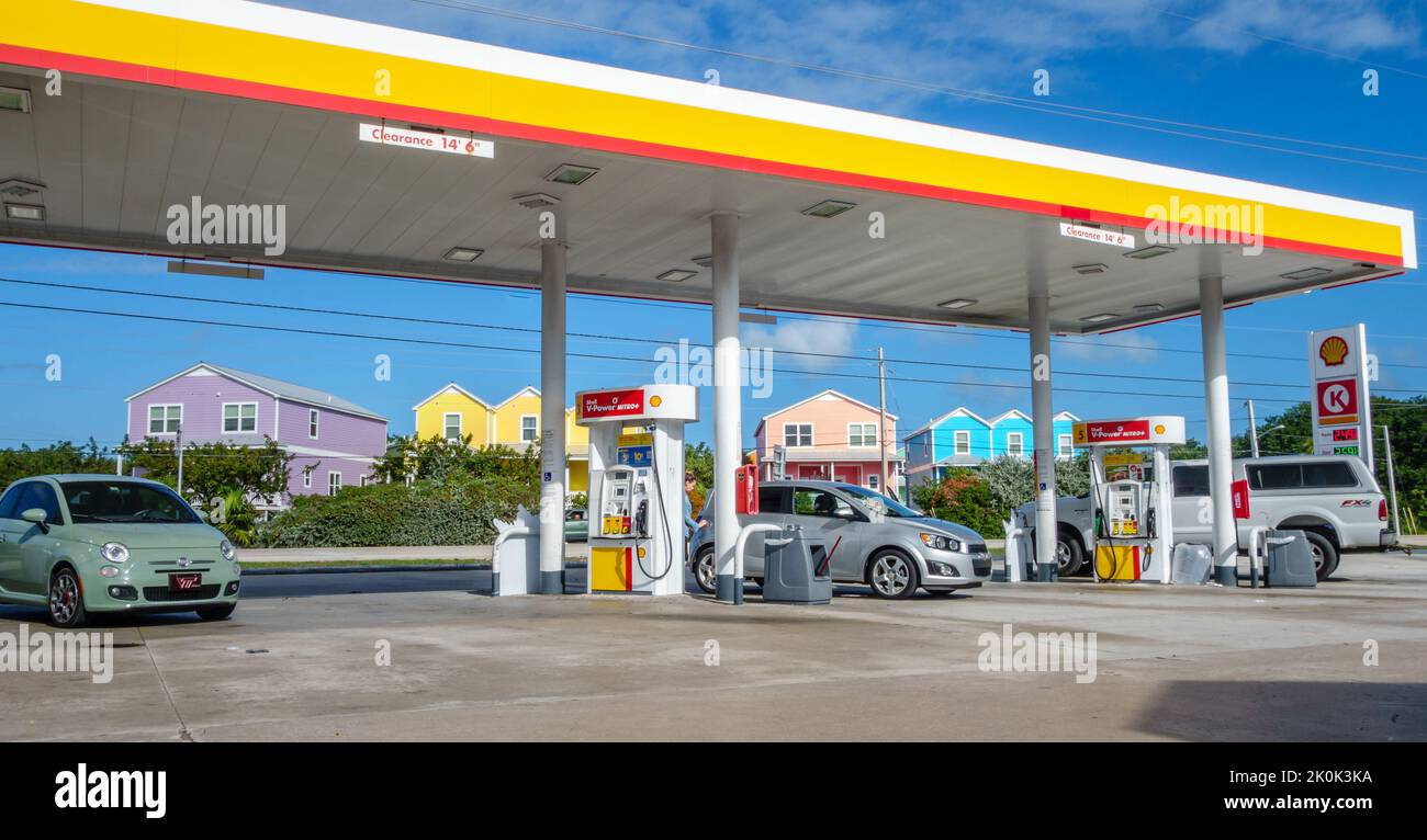 Key West, FL, USA, 28. Dezember 2016: Autos füllen sich an der Tankstelle mit bunten Häusern im Hintergrund. Stockfoto