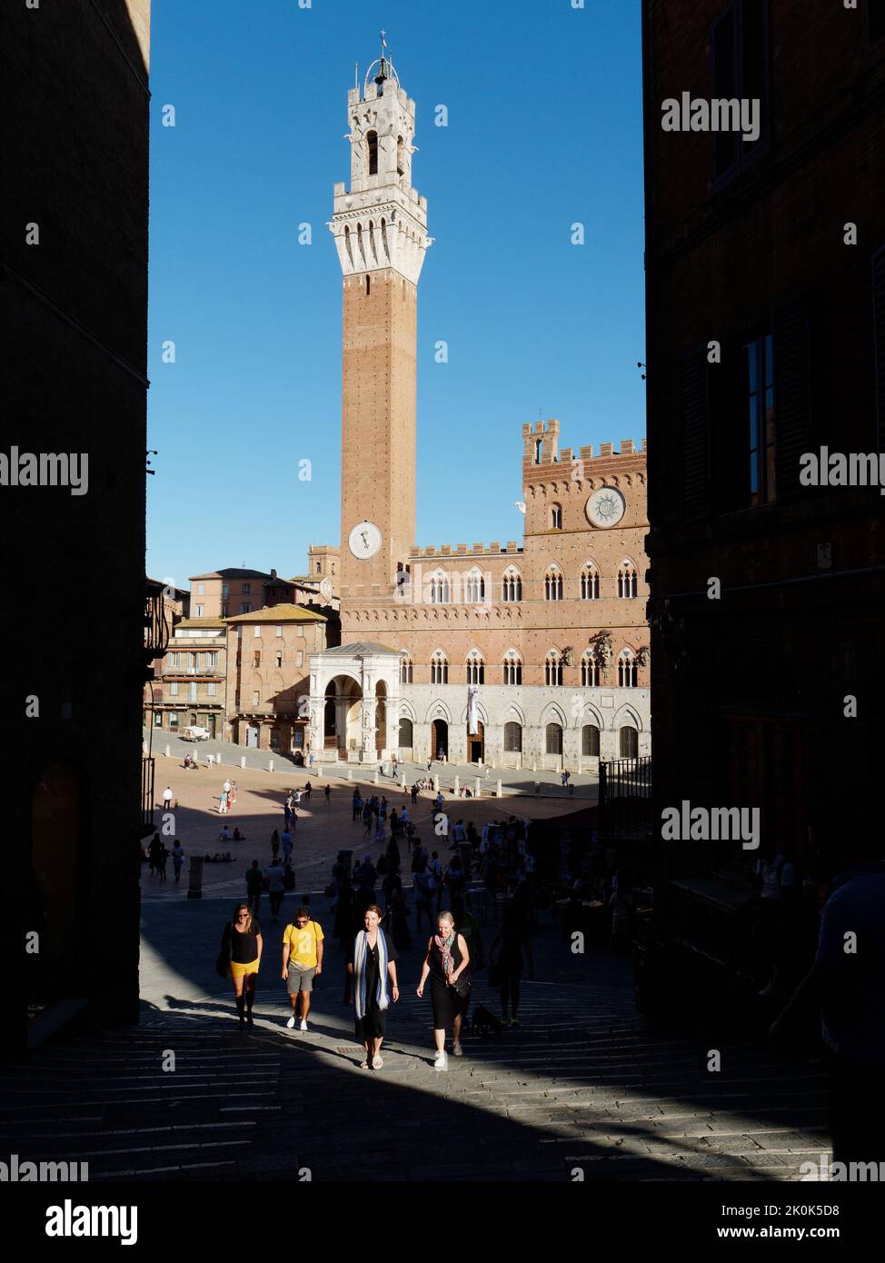 Siena, Toskana, Italien. Mit Blick auf Il Campo, eine mittelalterliche piazza. Ein Lichtstrom hebt Touristen hervor, die im Vordergrund weggehen. Stockfoto