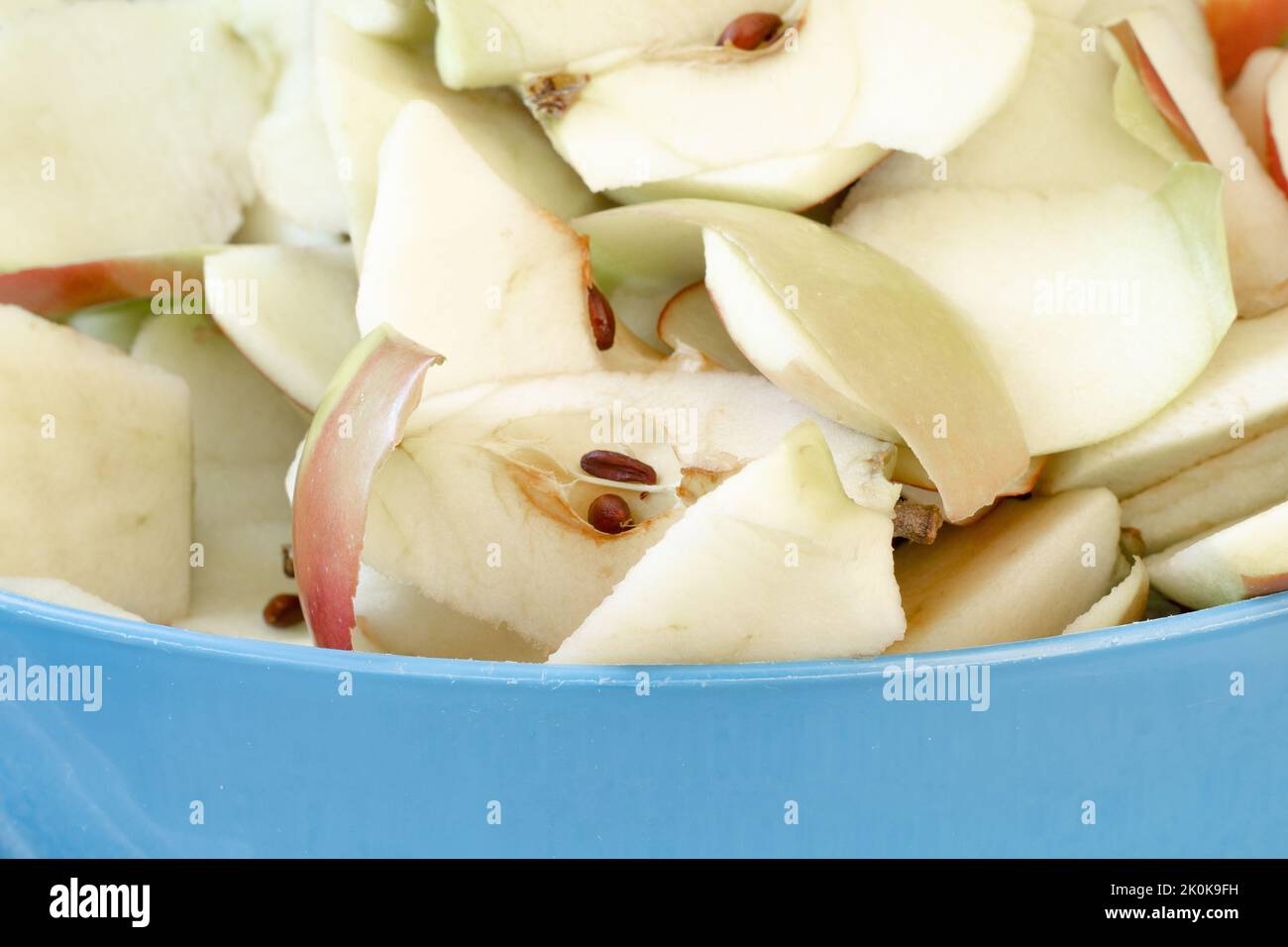 In Scheiben geschnittene Äpfel und Peelings in einer blauen Schüssel, fertig zum Kompostieren Stockfoto