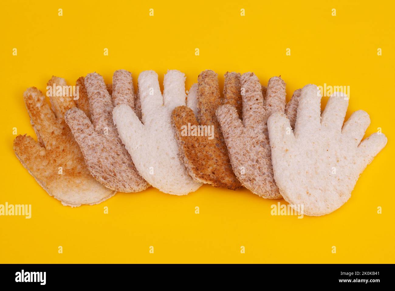 Hände aus geröstetem, geschnittenem Brot. Multikulturell übergibt Konzept auf gelbem Hintergrund Stockfoto