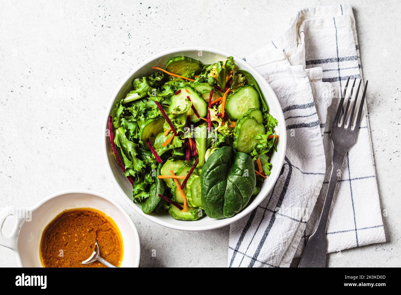 Grüne Salatschüssel mit Senfdressing, Draufsicht. Veganes Lebensmittelkonzept. Stockfoto
