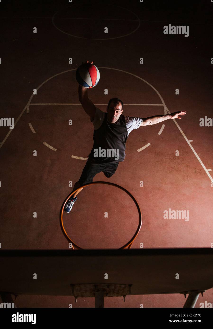 Basketballspieler in schwarz-weißen Sportkleidung springen und machen Dunk beim Training auf Sportplatz Stockfoto