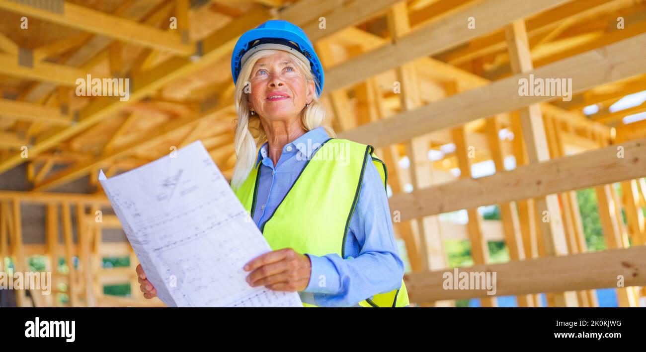 Ältere Frau mit Schutzhelm und gelber Weste, die als Ingenieurin arbeitet und Expertise beim Bau von ökologischen erneuerbaren niedrigen Energien macht Stockfoto