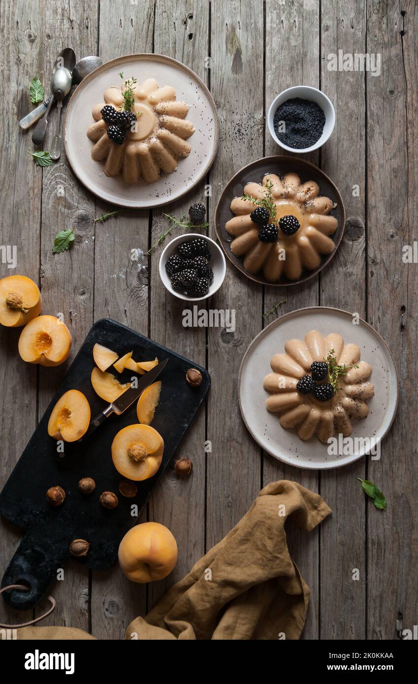 Flache Laie aus angerichtet servierten Panna Cotta mit Pfirsich und Mohnsamen auf dem Tisch mit Brombeere Stockfoto