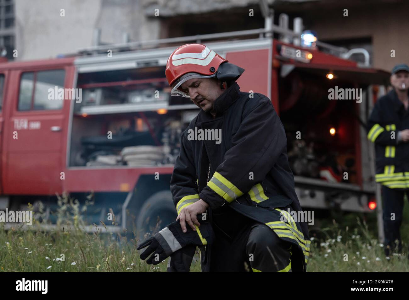 Deprimierter und müder Feuerwehrmann in der Nähe des Feuerwehrwagens. Stockfoto