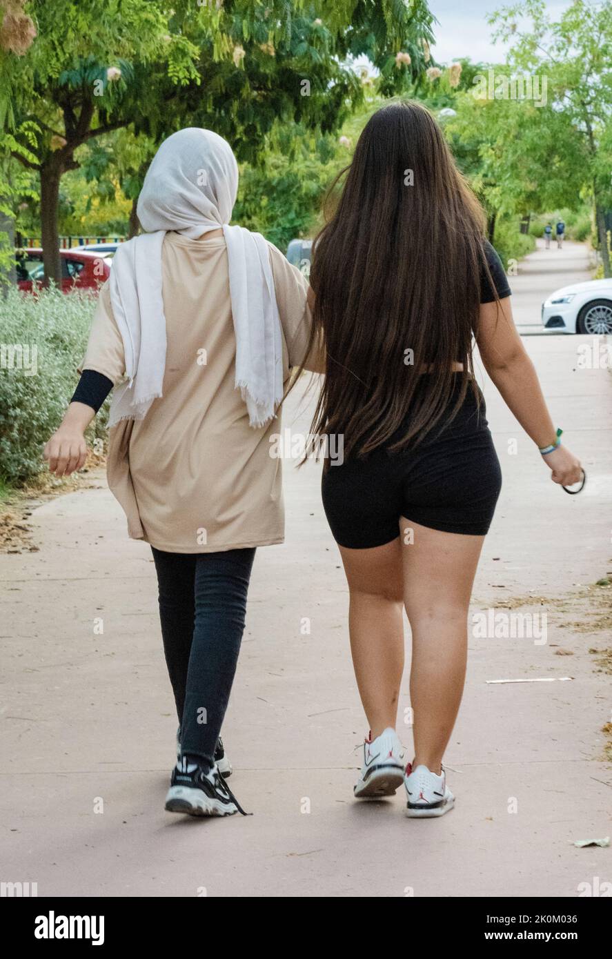 Arabische und europäische Teenager-Mädchen gehen und genießen Zeit zusammen in einem Park. Multikulturelles Konzept. Stockfoto