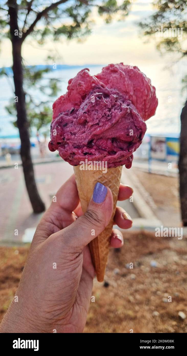 Eis-Eis-Kegel gehalten, um die heiße Sommerstadt. Womans Hand. Stockfoto