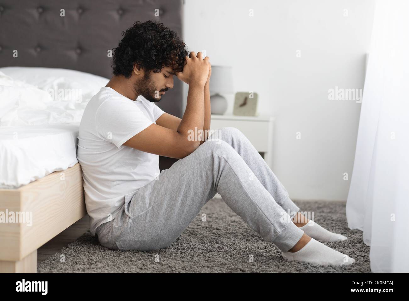 Deprimierter junger inder, der zu Hause am Bett sitzt Stockfoto