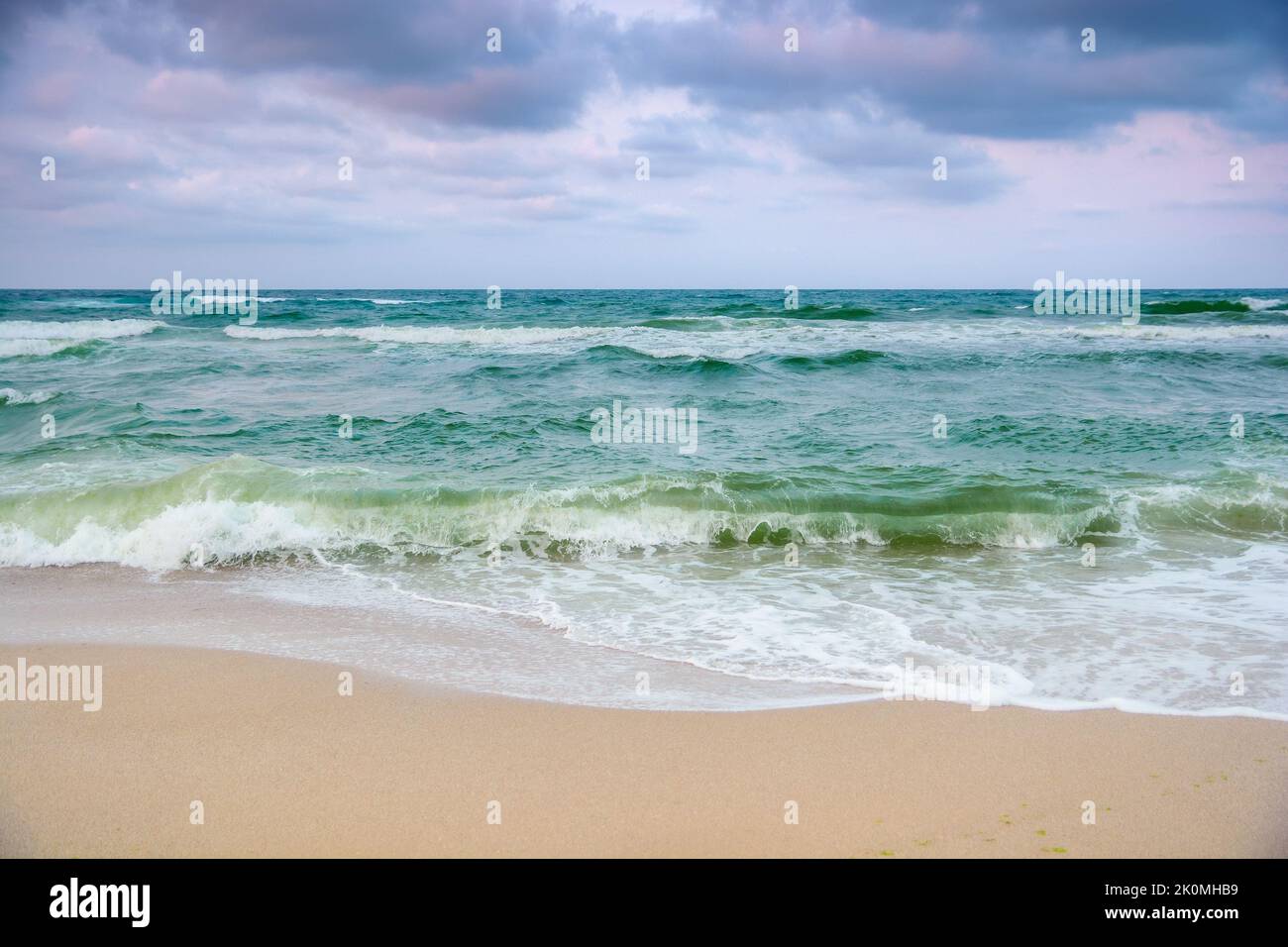 Stürmisches Wetter in der Samtsaison. seascape mit bewölktem Abendlicht. Wellen krachend Sandstrand. Windiges Wetter Stockfoto
