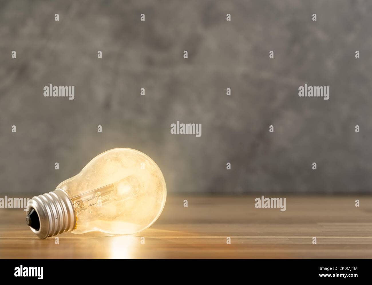 Nahaufnahme einer leuchtenden einzelnen Glühbirne auf einem unscharfen grünen Hintergrund. Stockfoto