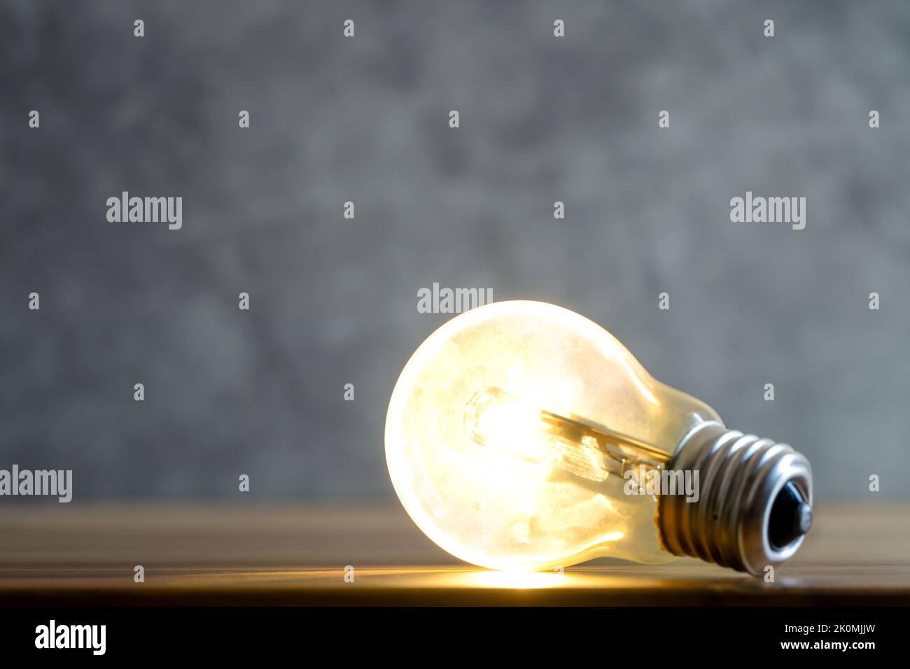 Nahaufnahme einer leuchtenden einzelnen Glühbirne auf einem unscharfen grünen Hintergrund. Stockfoto