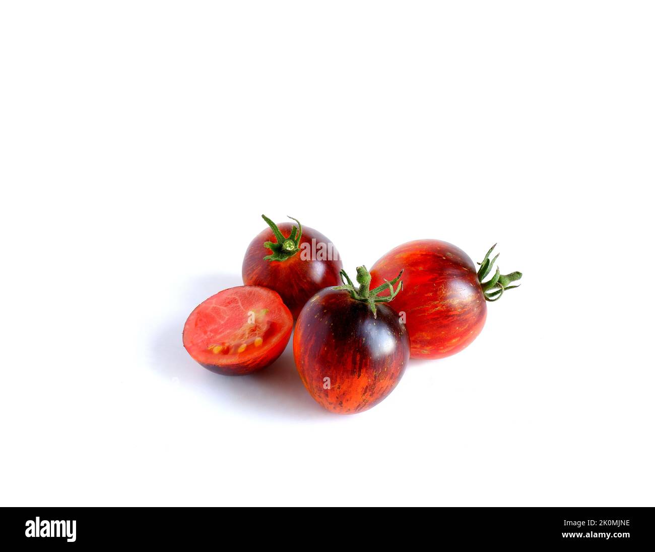Runde violett-rote Tomaten, ganze und halbe auf weißem Hintergrund. Stockfoto