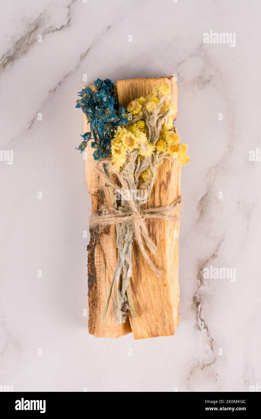 Verschmieren mit palo santo. Palo santo-Stäbchen mit trockenen aromatischen Kräutern auf weißem Marmortisch. Raumbegasungsritual für Yoga und Stockfoto