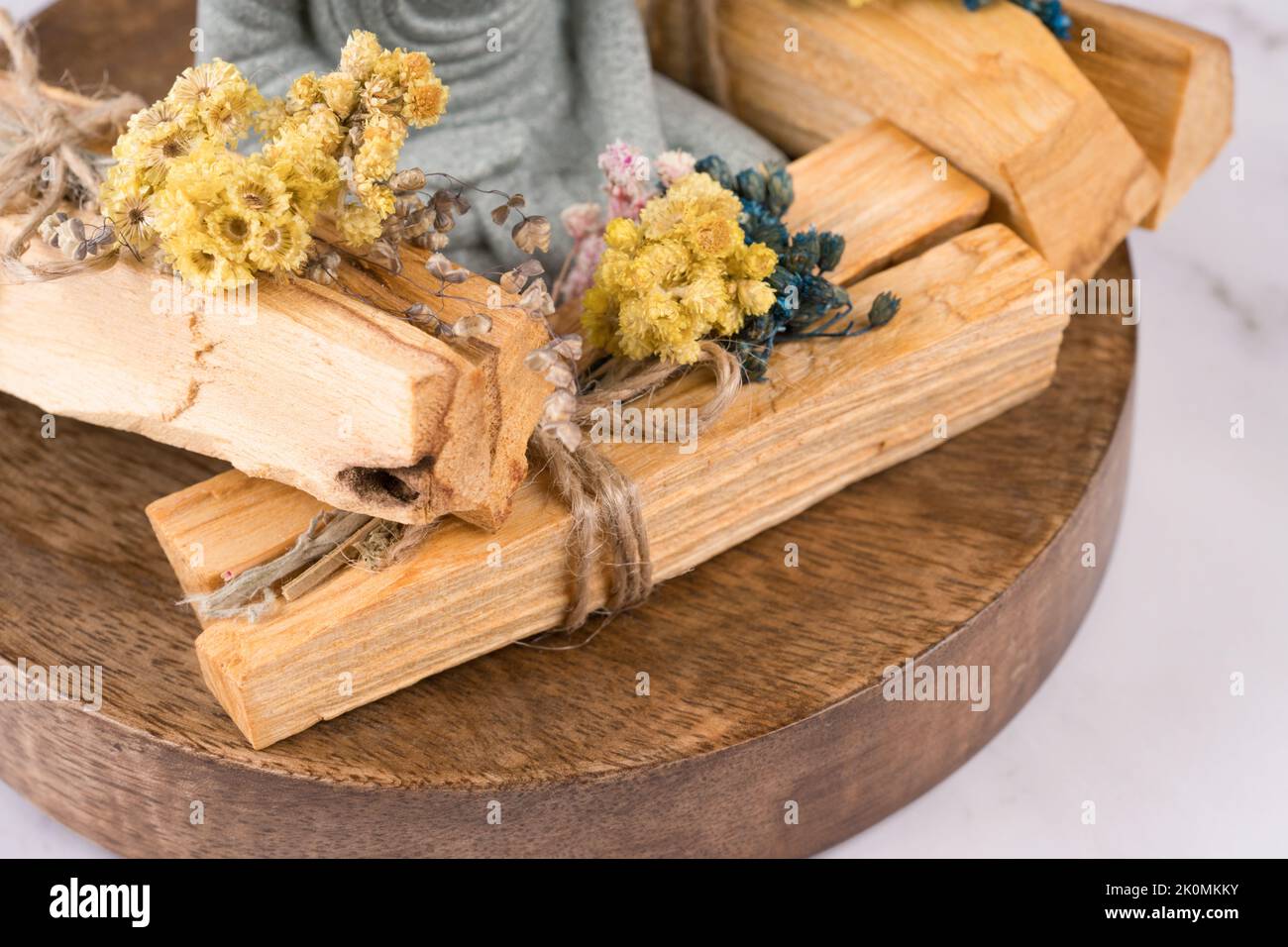 Nahaufnahme der palo santo Sticks Kräuter und Buddha-Statue auf weißem Marmortisch. Raumbegasungsritual für Meditation und spirituelle Praktiken. Incens Stockfoto