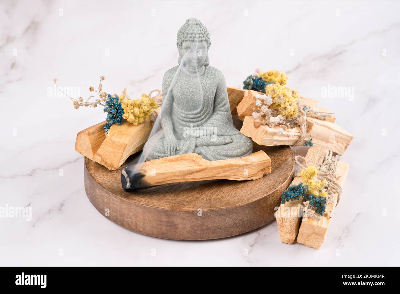 Räucherstäbchen brennen. Verschmieren mit palo santo-Stäbchen, verziert mit trockenen Kräutern und Buddha-Statue auf weißem Marmortisch. Ritual zur Raumbegasung für Meditati Stockfoto