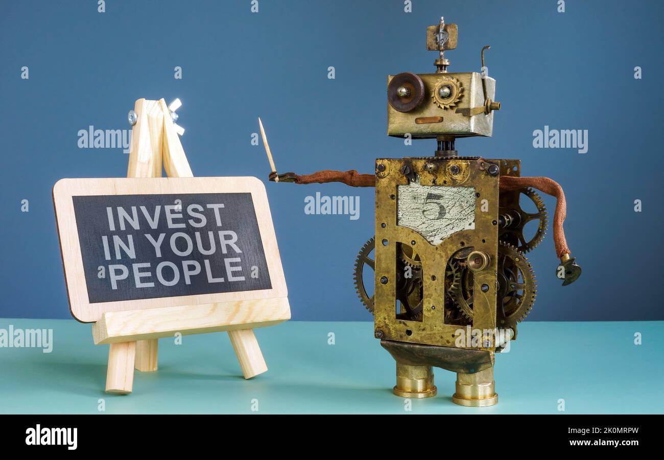 Roboter in der Nähe der Tafel mit Schild investieren Sie in Ihre Leute. Stockfoto