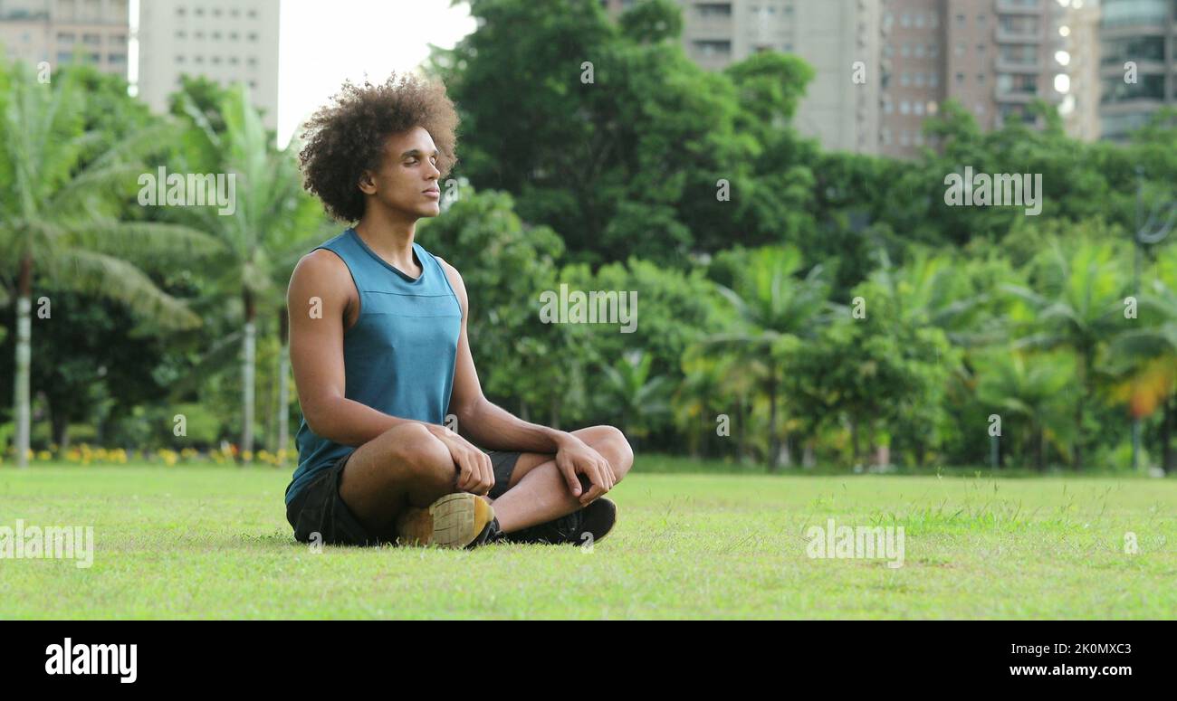 Junger afrikanischer schwarzer Mann saß auf Gras in Meditation und Kontemplation Stockfoto