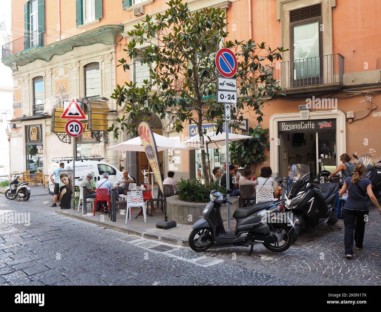 Typische neapolitanische Straßenszene mit Leuten, die sich gesellten und Kaffee trinken, und geparkten Motorroller überall. Neapel, Kampanien, Italien Stockfoto