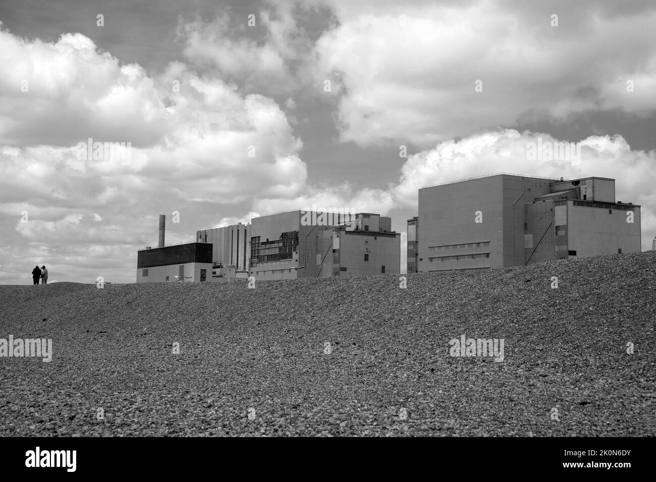 Monochrom-Bild von zwei Menschen, die am Kernkraftwerk Dungeness in Kent, England, vorbeigehen. Stockfoto