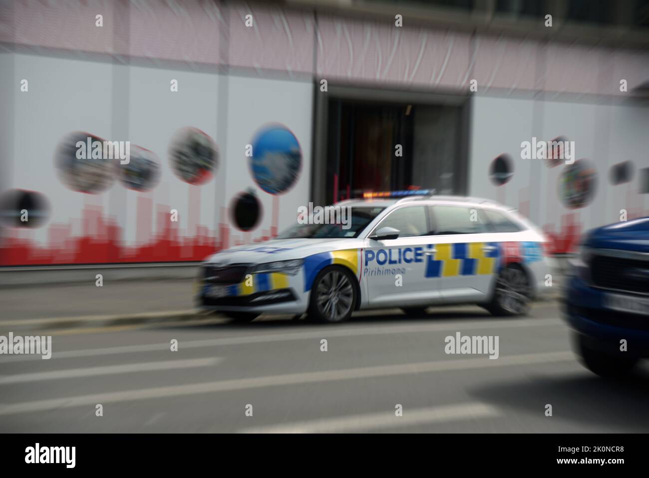 Ein Polizeiauto mit blinkenden Lichtern und Sirenen, die heulen, führt zu einem Notfall in Christchurch, der Quake City von Neuseeland. Das Bild ist radial verzerrt Stockfoto