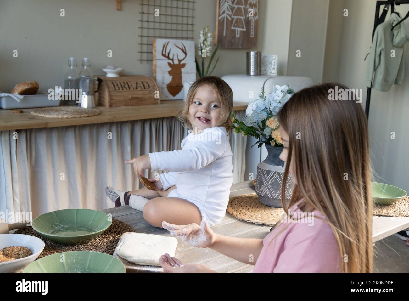 Glückliche Kinder und ihre Familie kochen gemeinsam leckere Süßigkeiten.das Baby sitzt auf dem Tisch.das Konzept eines Familienurlaubs zu Hause und während der Quarantäne. Stockfoto