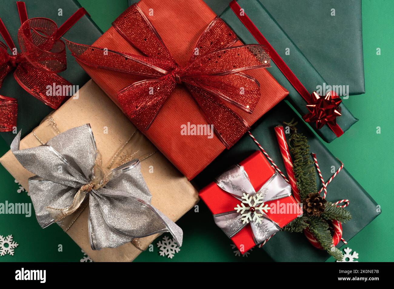 Geschenkschachteln aus rotem Papier und Bastelpapier auf grünem Hintergrund. Das Konzept der Feiertage, umweltfreundliche Verpackung, Online-Shopping für Weihnachten, Neujahr, Valentinstag, Muttertag. Flach liegend. Stockfoto