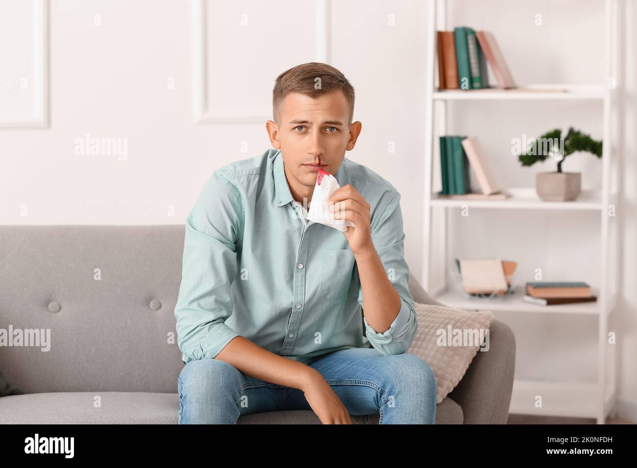 Junger Mann mit Nasenbluten und Gewebe zu Hause Stockfoto