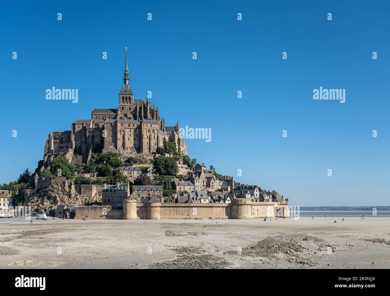 Mont St. Michel, Normandie, Frankreich - 8. Juli 2022: Die Struktur aus braunem Stein auf seinem Felsen, umgeben von Sandflächen bei Ebbe und blauem Himmel. Stockfoto