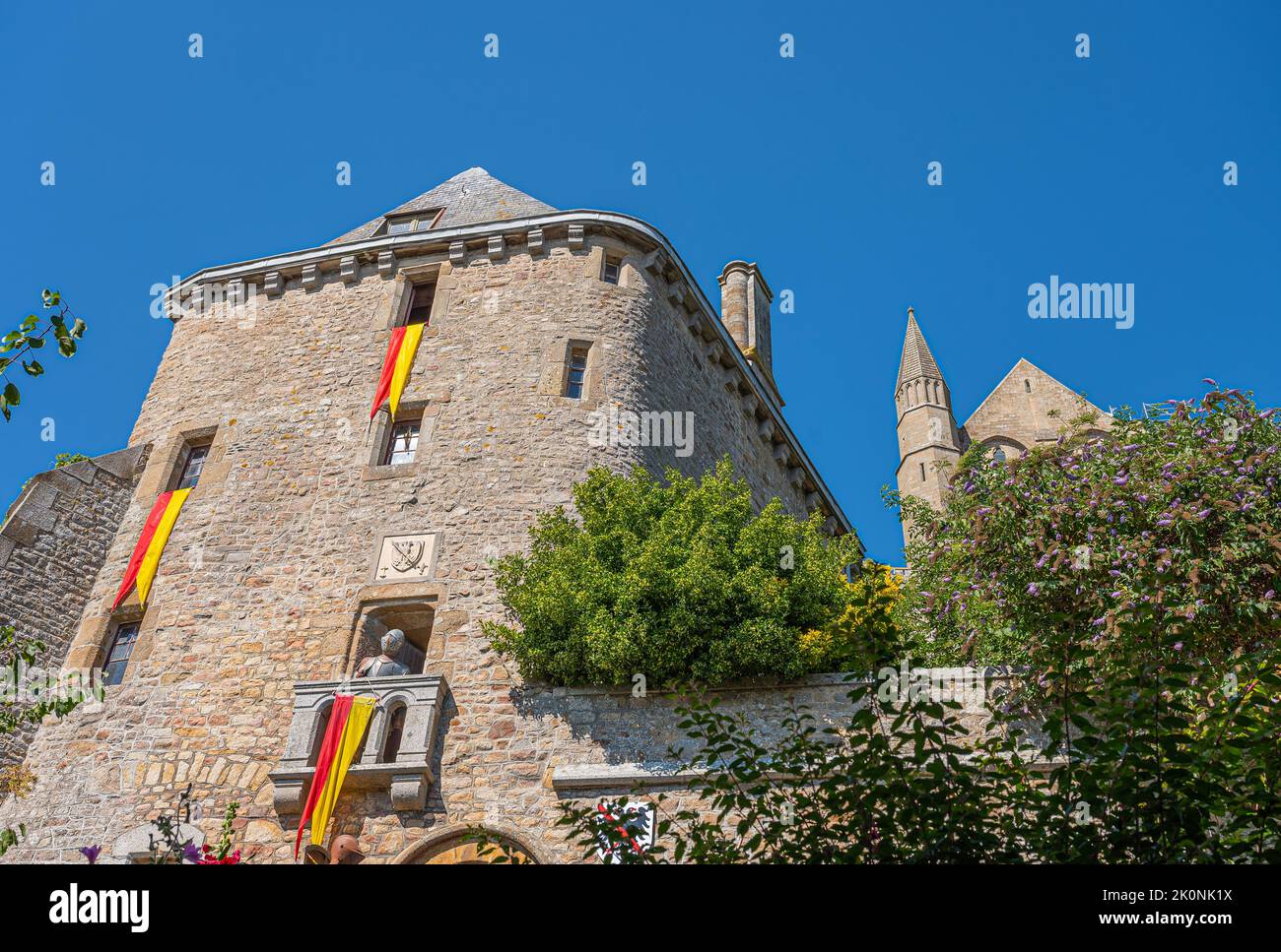 Mont St. Michel, Normandie, Frankreich - 8. Juli 2022: Braune Stein Burg Struktur mit rot-gelben Normandie Farben Banner unter blauem Himmel dekoriert. Einige Stockfoto