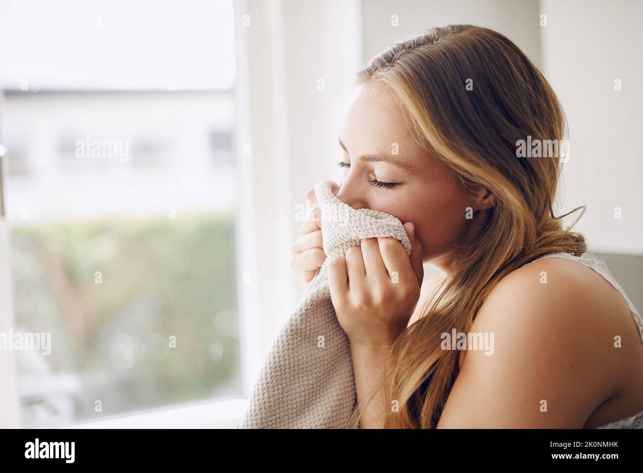 Eine junge Frau riecht zu Hause nach frischer Wäsche. Stockfoto