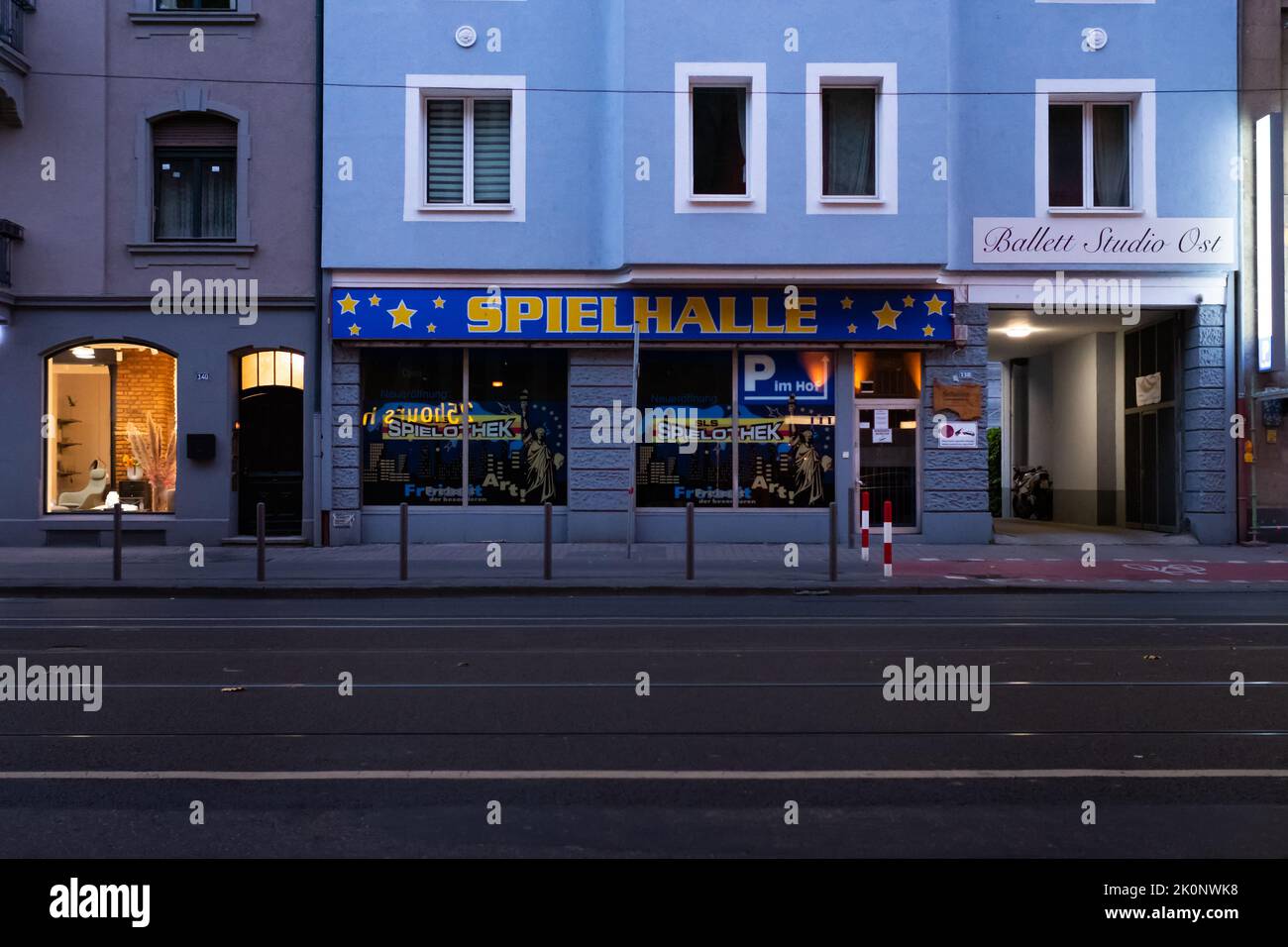 Spielhalle in der Stadt. Gebäudefassade mit großer Werbung zur Straße hin. Dunkler Morgen mit einer leeren Straße. Stockfoto
