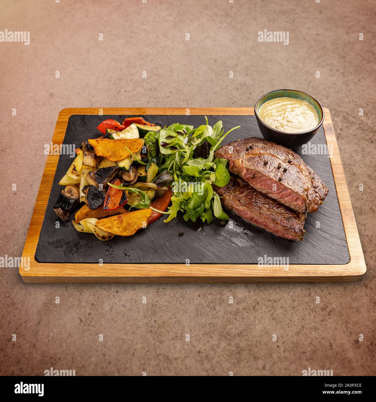 Marinierte, knochenlose, zarte Schweinekoteletts, garniert mit gegrilltem Gemüse und Salat, serviert mit Senfsoße Stockfoto