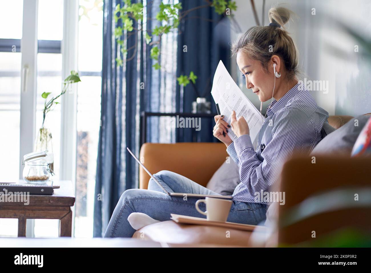 Reife professionelle asiatische Frau, die von zu Hause aus arbeitet und während eines Online-Videotreffens ein Papierdokument zeigt Stockfoto