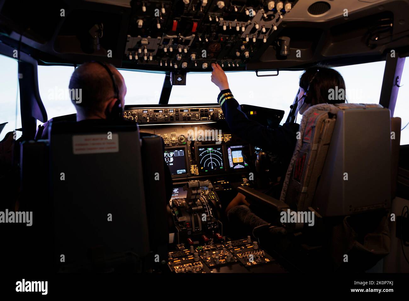 Frau Copilot Unterstützung Kapitän zum Start und Flugzeug fliegen, mit Tasten auf Dashboard-Befehl im Pilot-Cockpit. Airliner fliegen Flugzeug Jet mit Navigations-Windschutzscheibe und Bedienfeld. Stockfoto