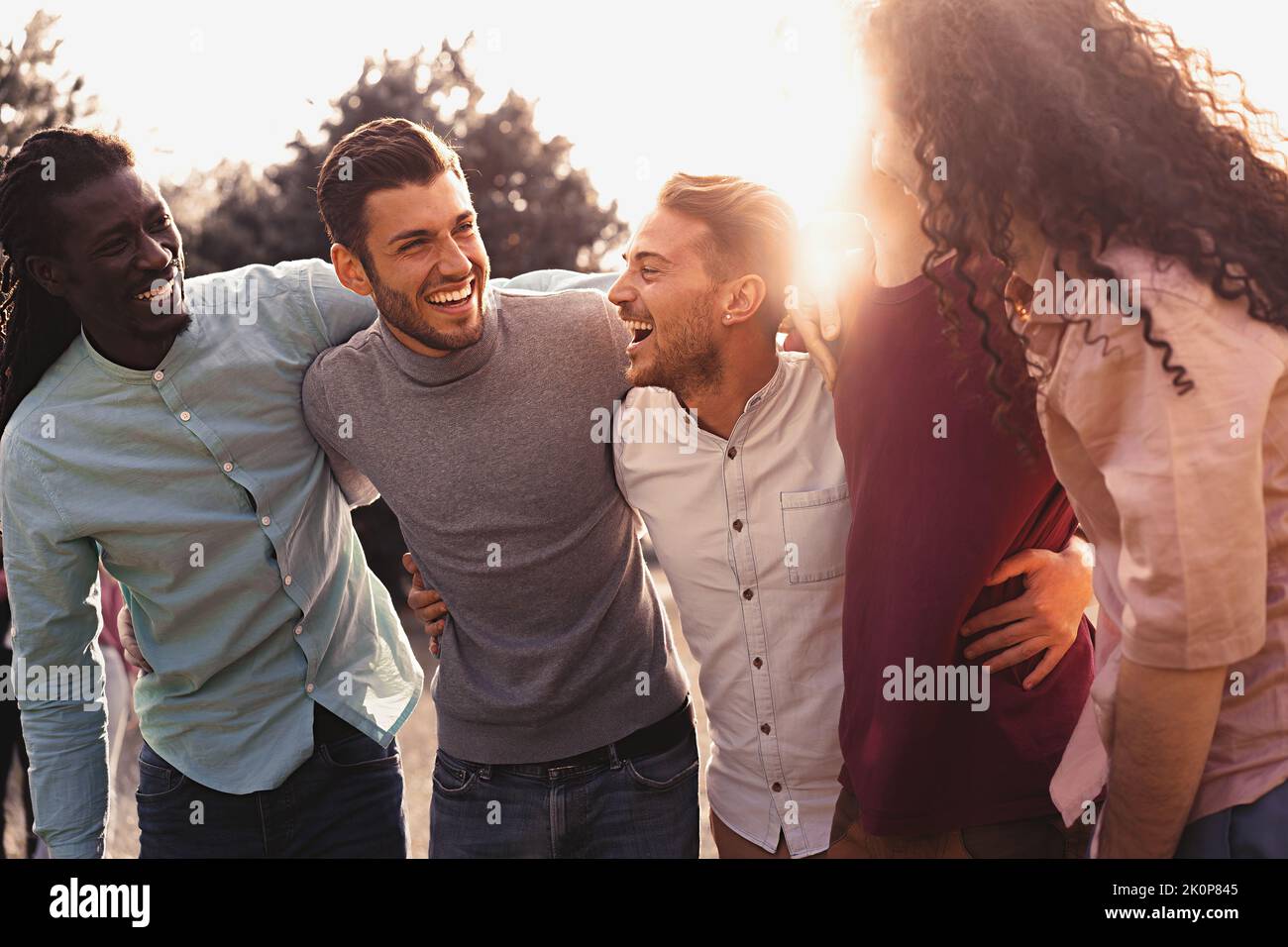 Multiethnische Gruppe positiver Freunde, die sich im Freien umarmen und Spaß haben. Junge lächelnde Menschen, die zusammen lachen, genießen die Gemeinschaft - fröhliche Jahrtausende Stockfoto
