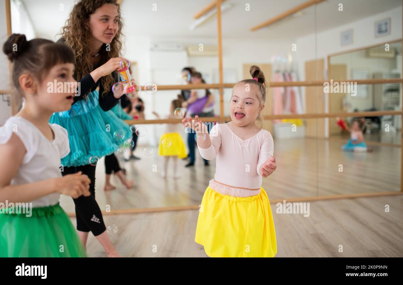 Kleine Mädchen mit Down-Syndrom und Tanzlehrende, die Spaß im Ballettschulstudio haben. Stockfoto