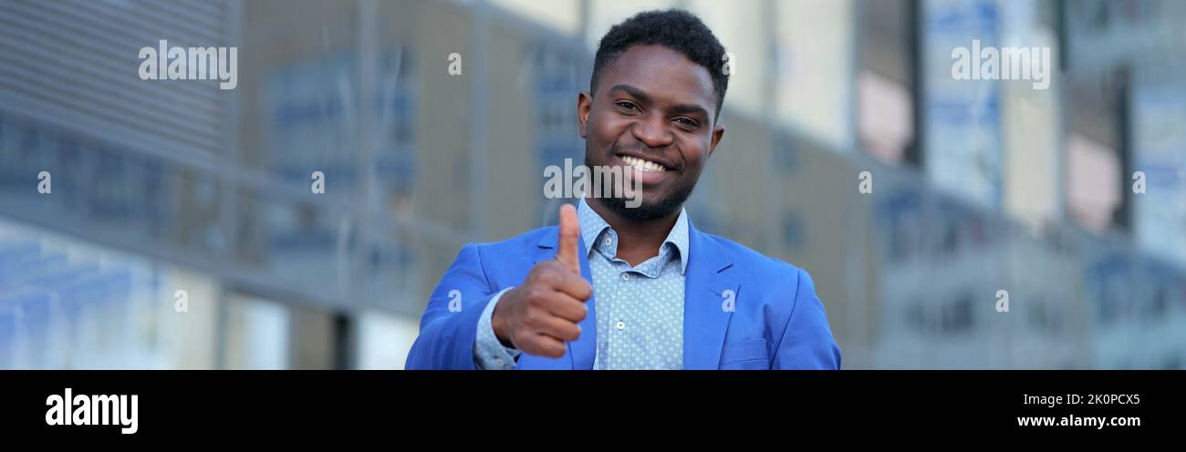 Afroamerikanischer Geschäftsmann in blauem Blazer zeigt Daumen hoch Stockfoto
