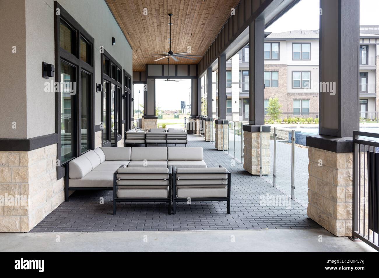 Dekorative Terrasse mit Blick auf den modernen Wohnkomplex, Sitzbereich mit Sofas und Sesseln. Architektur und Entspannung Stockfoto