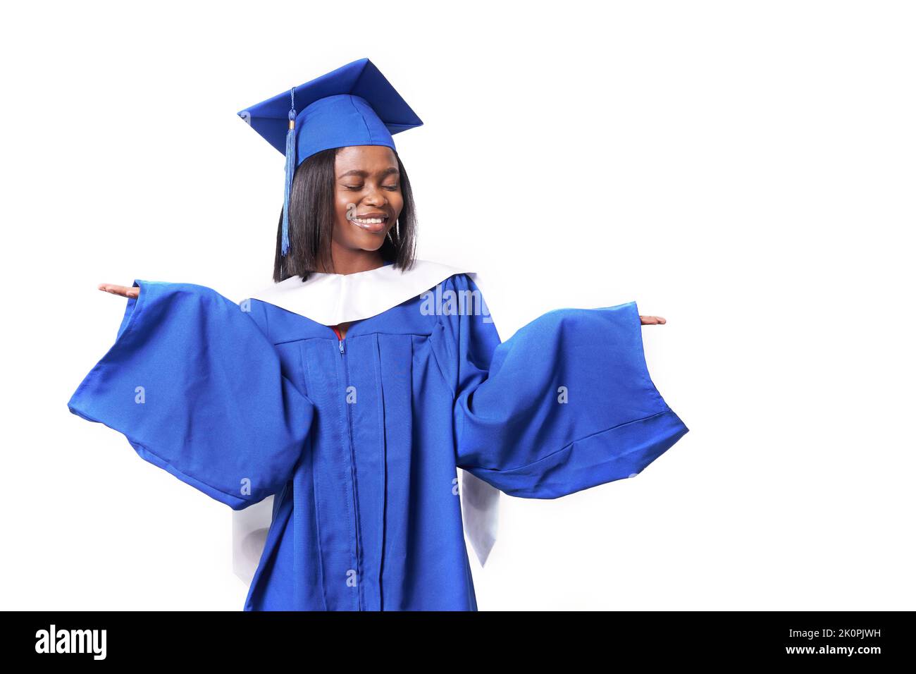 Eine afroamerikanische Frau in einer blauen Robe und einem Hut auf einem weißen, isolierten Hintergrund lächelt und breitet ihre Arme mit geschlossenen Augen aus. Modellbildung für Ihr Bildungsprodukt. Hochwertige Fotos Stockfoto