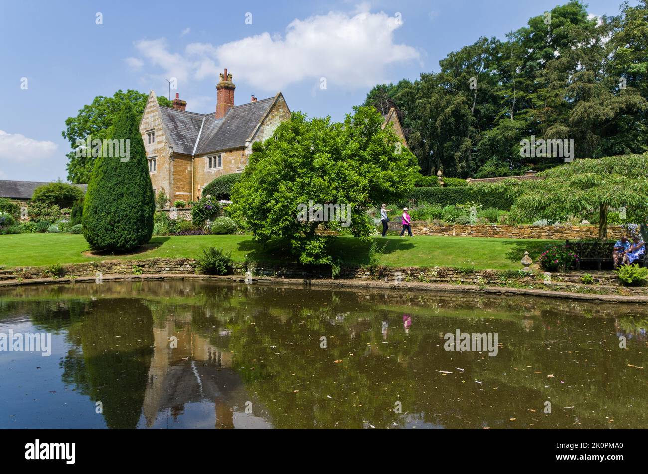 Ein Sommerblick über den Ziersee zum Herrenhaus, Coton Manor Gardens, in der Nähe von Guilsborough, Northamptonshire, Großbritannien Stockfoto