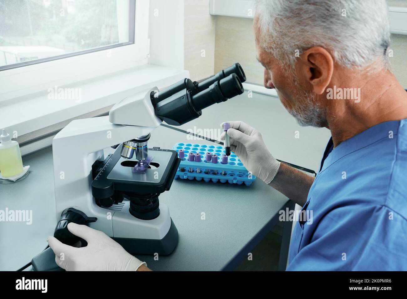 Laborant untersucht Blutproben mit einem medizinisch-wissenschaftlichen Mikroskop im Krankenhauslabor Stockfoto