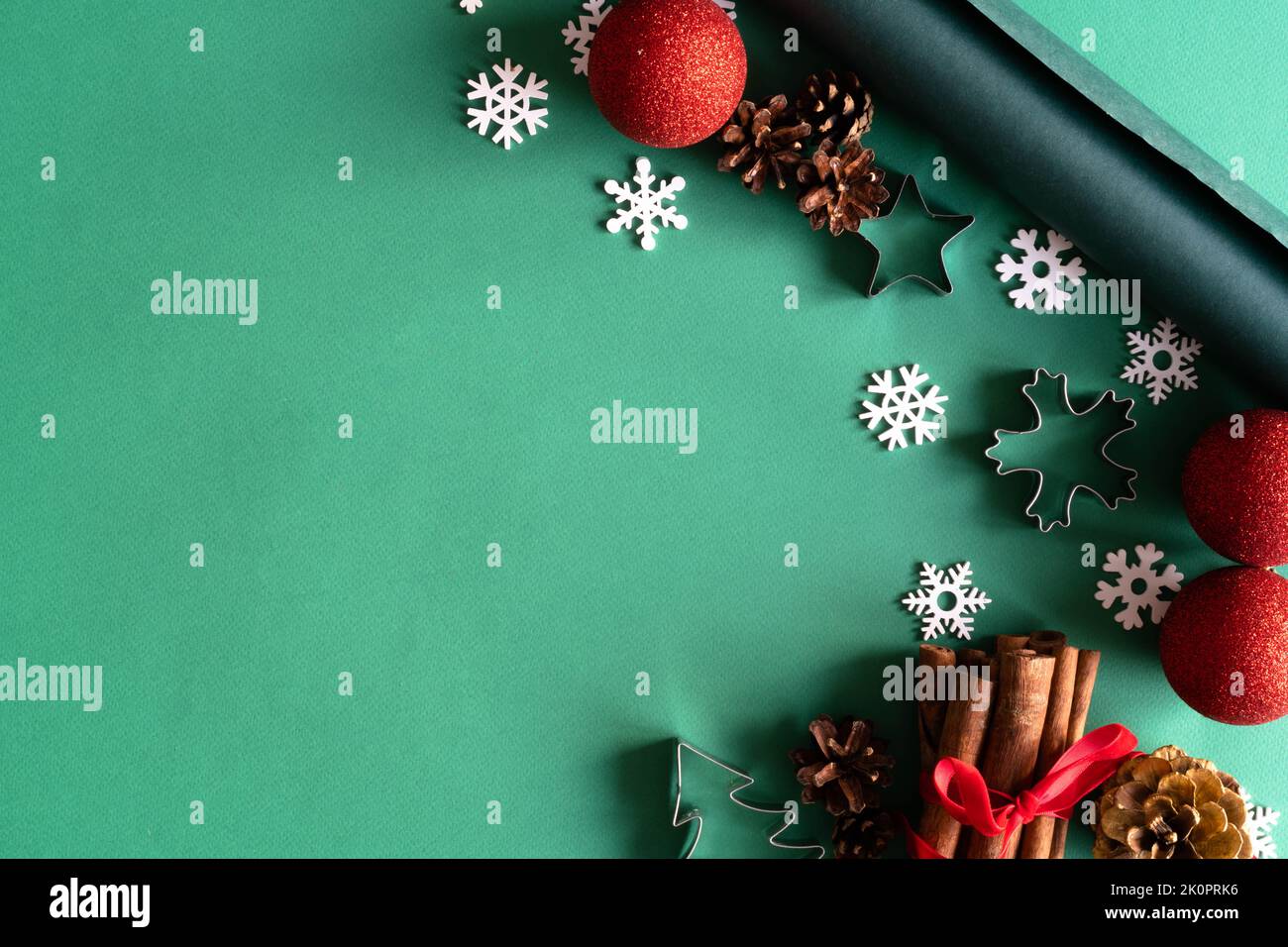 Weihnachtliche Naturdekorationen aus Holz, rote Kugeln, Geschenkbox und Notizblock auf grünem Hintergrund. Weihnachtsgruß-Design. Flach liegend, Draufsicht, Kopierbereich. Das Konzept von Urlaub und Neujahr. Stockfoto