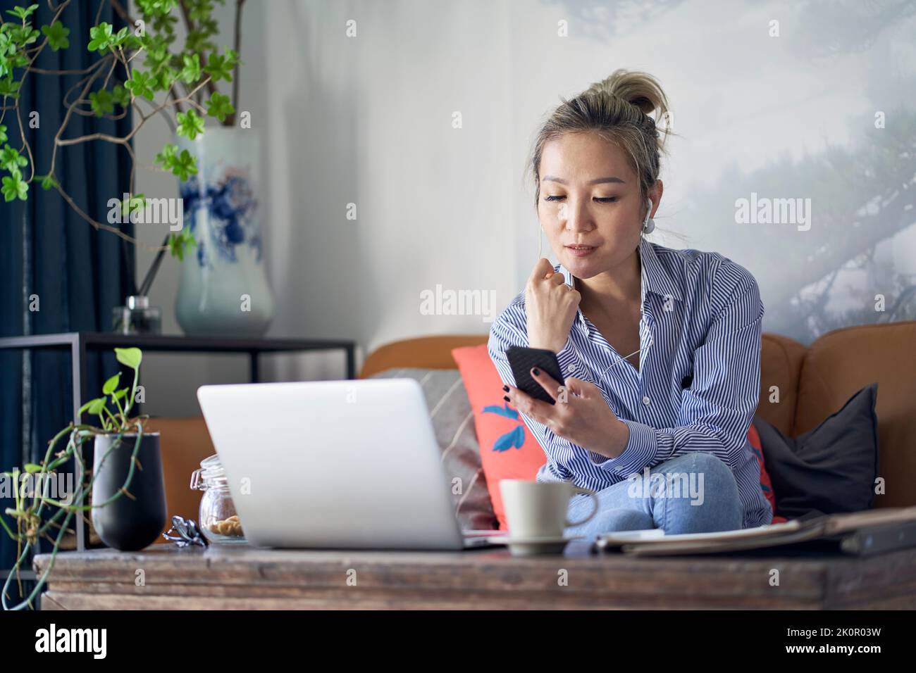 Professionelle asiatische Geschäftsfrau arbeitet von zu Hause aus Video-Chat mit Handy und Laptop-Computer Stockfoto