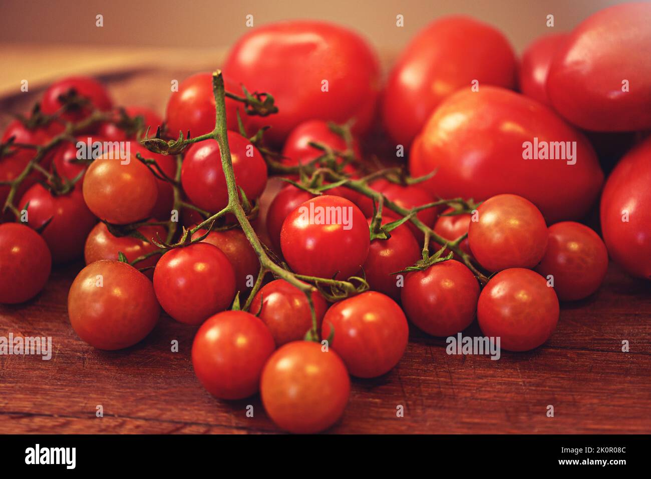 Tomatoey Schätze. Eine Pflaume und Kirschtomaten auf einem Tisch in einer Küche. Stockfoto