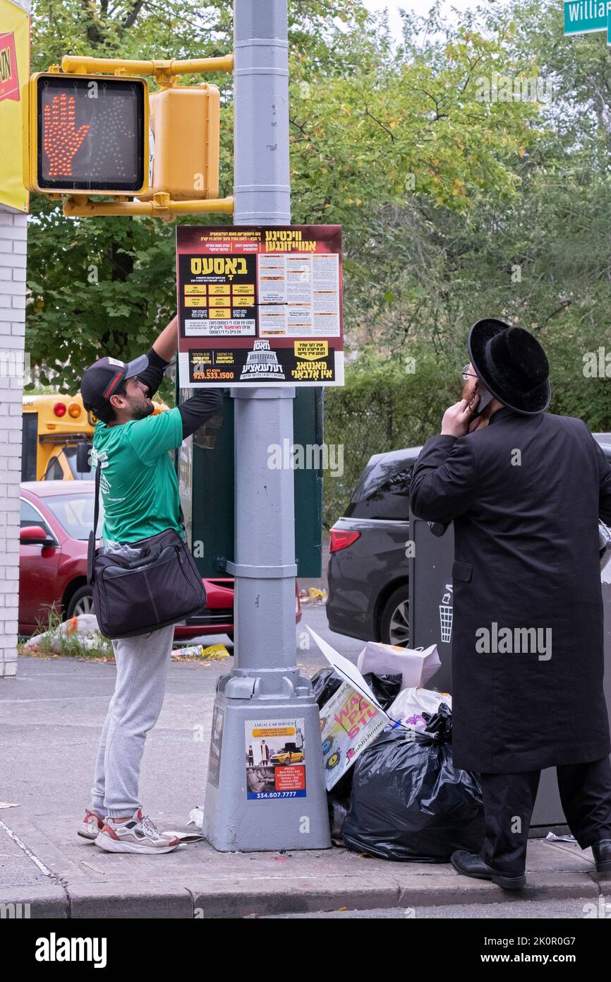 Ein chassidischer jüdischer Mann sieht zu, wie ein Schild aufgestellt wird, um eine Kundgebung anzukündigen, die gegen die Regeln des EDS zur Kontrolle der Lehrpläne privater Schulen Einspruch erheben soll. NYC. Stockfoto