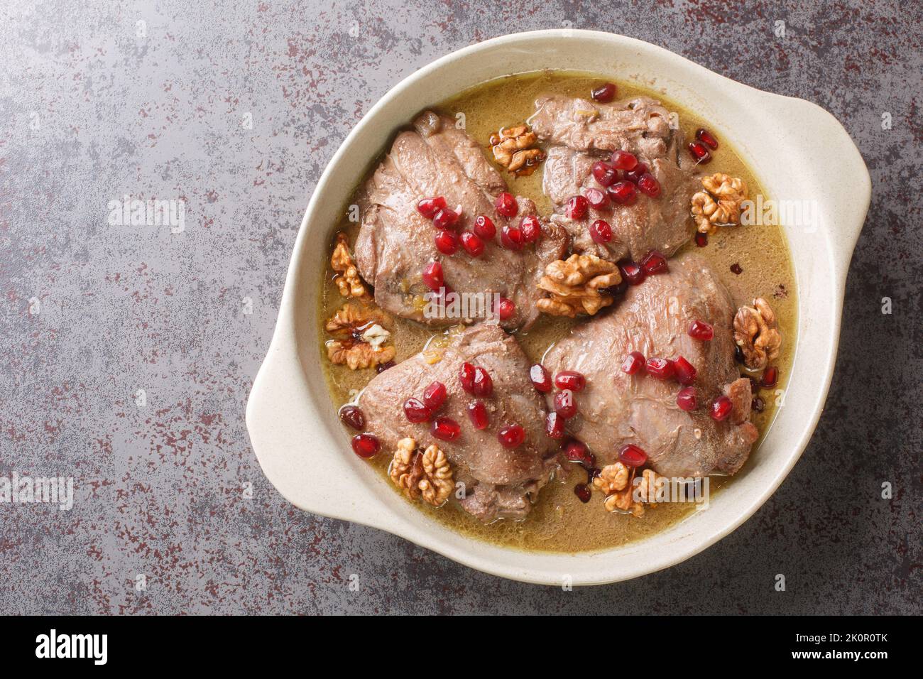 Khoreh Fesenjan zartes Huhn wird in einer Walnussgranatapfelsauce in einer Pfanne auf dem Tisch in der Nähe gekocht. Horizontale Draufsicht von oben Stockfoto