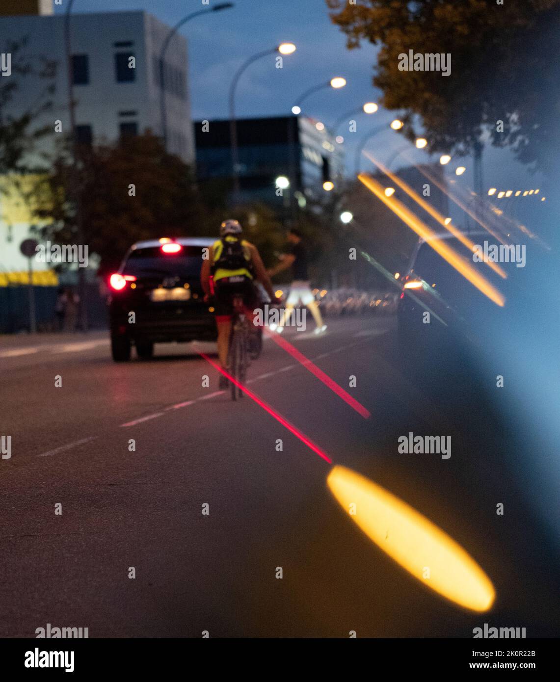 Defokused Nachtlicht Reflexionen. Auto und Biker stoppen, wie Fußgänger über die Straße.. Stockfoto