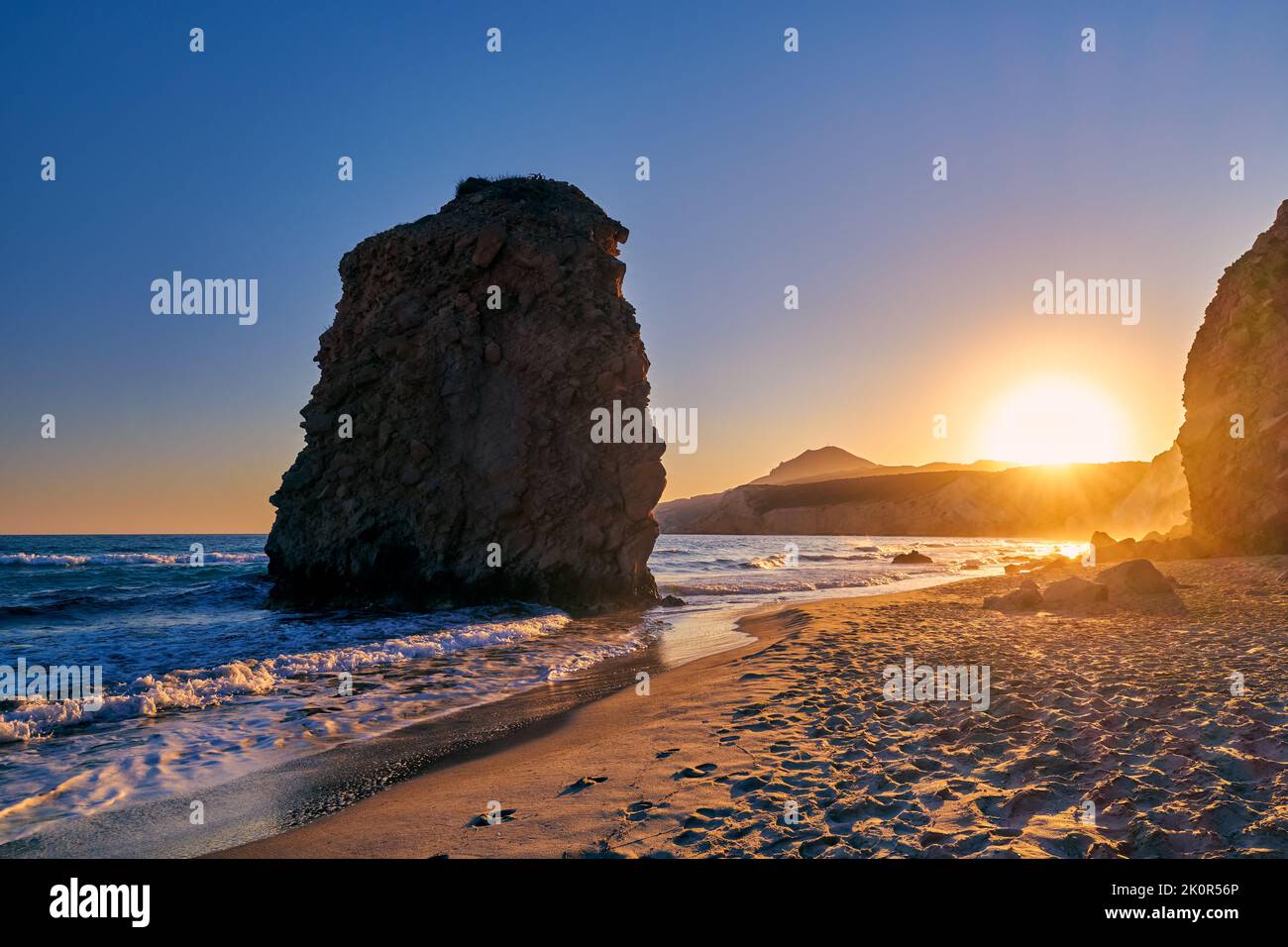 Farbenfroher Sonnenuntergang am Strand von Fyriplaka, Milos, Griechenland. Keine Menschen, niedrige Sonne. Ikonischer Fyriplaka einsamer Felsen gegen niedrige Sonne, farbenfrohen Himmel und Meer Stockfoto