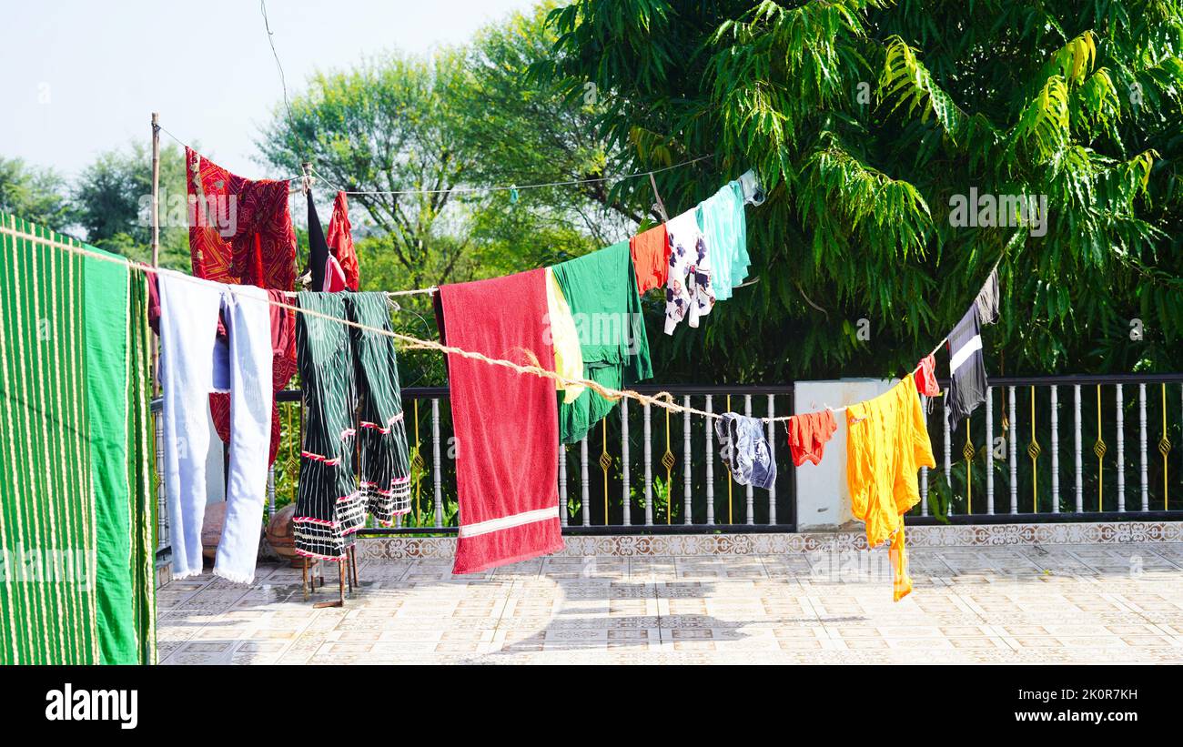 Wäscheleine mit Kleidung auf grünem Baumhintergrund. Wäschetrocknung auf dem Dach. Stockfoto